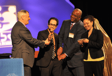 Ben Corey performs on stage at a corporate magic show.